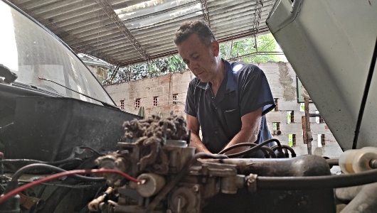 Ramon Caro revisa un vehículo en su taller de mecánica, ubicado en área de influencia del Metro de la 80.